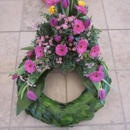 Begravelseskrans med rosa blomster og hvidt bånd