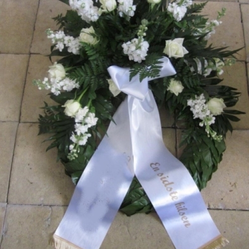 Begravelseskrans med hvide blomster, grønt og hvidt bånd