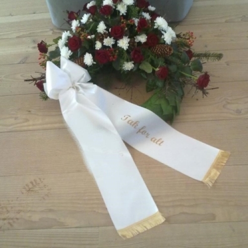 Begravelseskrans med tulipaner og lyse nelliker med bånd