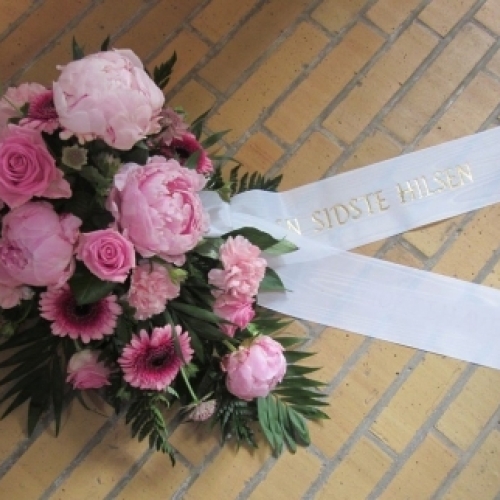 Begravelseskrans i pink nuancer med hvidt bånd med teksten En sidste hilsen