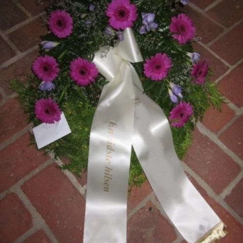 Begravelseskrans med røde roser, hvide blomster og kogler med hvidt bånd