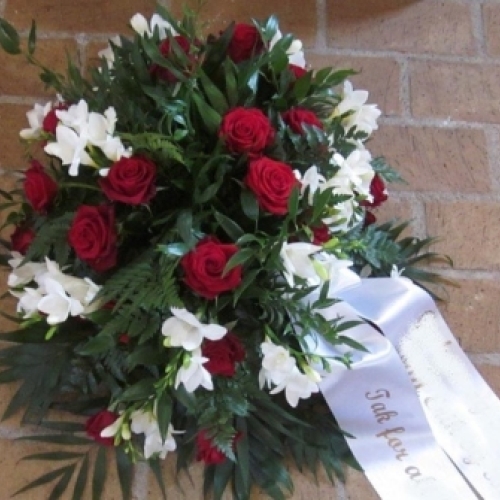 Begravelseskrans med røde roser, hvide blomster og hvidt bånd