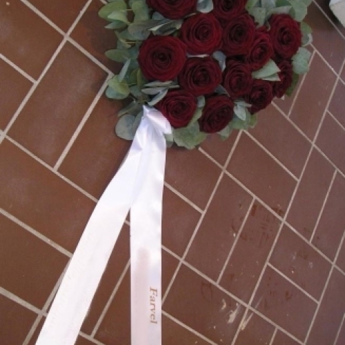 Rund begravelseskrans med røde roser og hvidt bånd