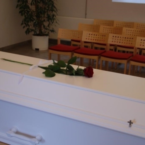 Naturlig kistepynt med orange og blå blomster samt grønt løv