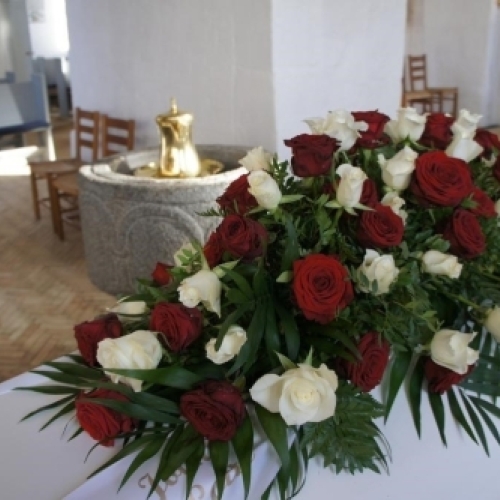 Enkel rød rose placeret på hvid kiste som symbol på personlig afsked