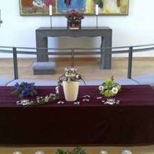 Urneopstilling i kirke på bord med blomsterdekoration