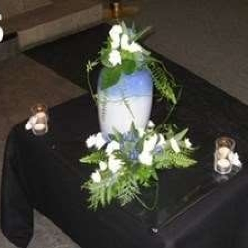 Urneopstilling med blomster og levende lys ved urnen