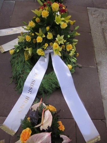 Begravelseskrans med hvide blomster, grønt og hvidt bånd