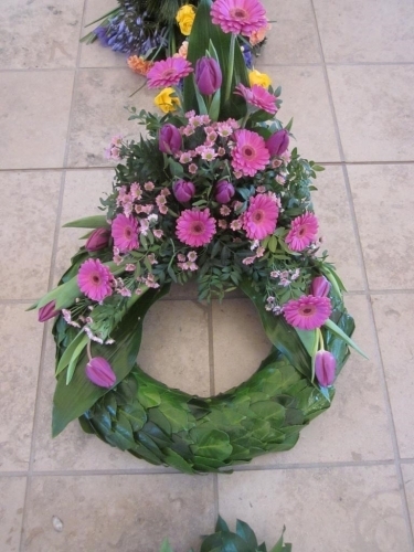 Begravelseskrans med rosa blomster og hvidt bånd