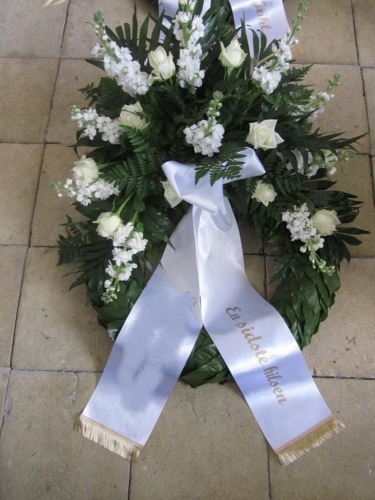 Begravelseskrans med hvide blomster, grønt og hvidt bånd