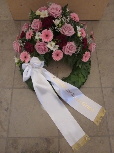 Begravelseskrans med rosa blomster og hvidt bånd