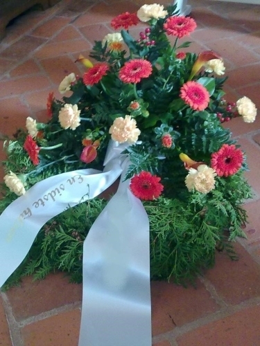 Begravelseskrans med røde og gule blomster med bånd