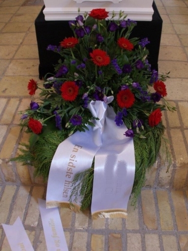 Begravelseskrans med hvide blomster og grønt med bånd