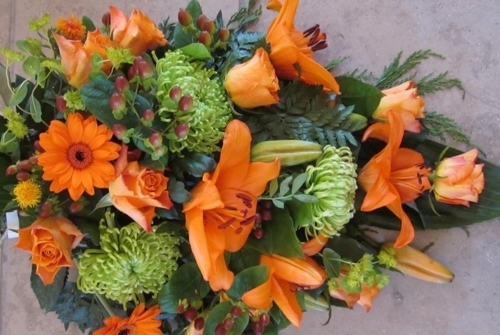 Bårebuket med orange liljer, roser og grønne blomster