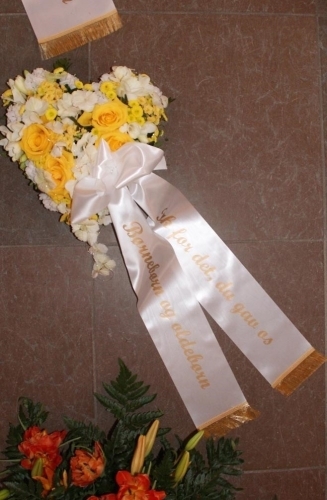 Begravelseskrans med gule roser, hvide blomster og hvidt bånd