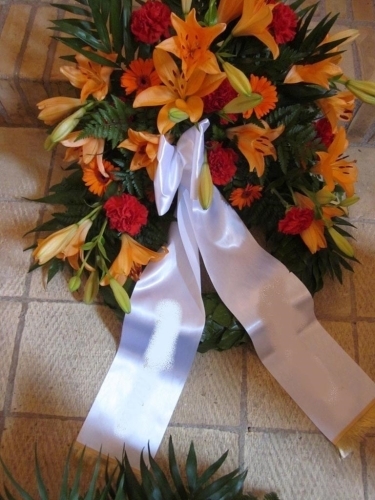 Begravelseskrans med hvide roser og lilla blomster med hvidt bånd