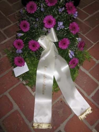 Begravelseskrans med røde roser, hvide blomster og kogler med hvidt bånd