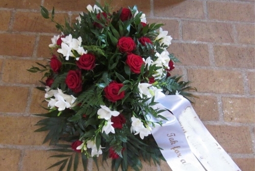 Begravelseskrans med røde roser, hvide blomster og hvidt bånd