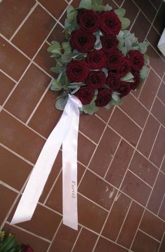 Rund begravelseskrans med røde roser og hvidt bånd