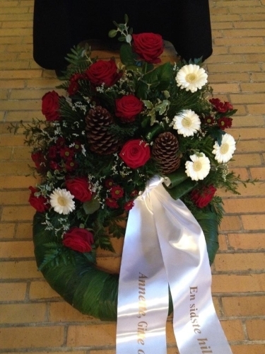 Begravelseskrans med røde roser, hvide blomster og kogler med hvidt bånd
