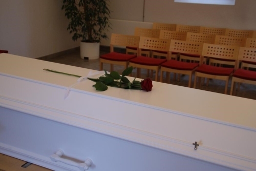 Naturlig kistepynt med orange og blå blomster samt grønt løv