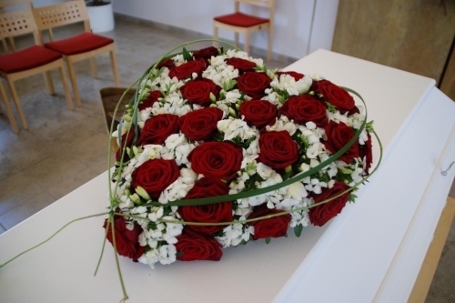 Kistepynt med gule og hvide blomster arrangeret på kiste i kirkerum