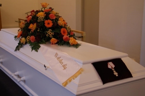 Hjerteformet kistepynt med røde roser og hvide blomster