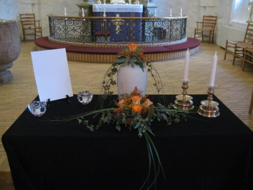 Hvid urne dekoreret med hvide roser, liljer og efeu til bisættelse