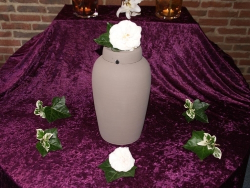 Urne med blå og hvide blomsterdekoration samt lys til bisættelse