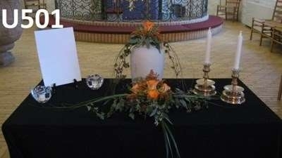 Urnedekoration i kirke med blomster og lys