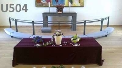 Urneopstilling i kirke på bord med blomsterdekoration