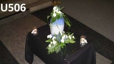 Urneopstilling med blomster og levende lys ved urnen